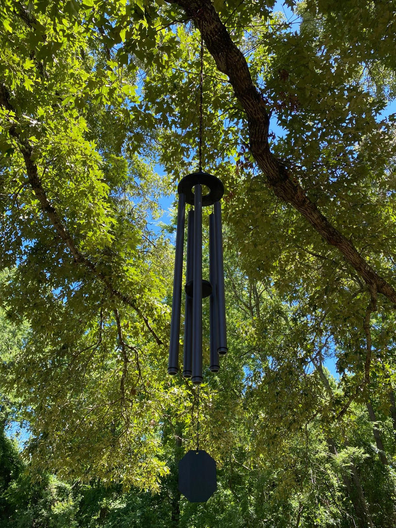 Court Haus wind chime hanging from a tree limb among green leaves