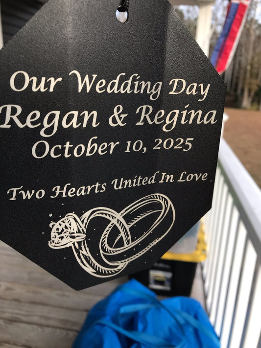 Close-up of a custom engraved wind chime sail reading Our Wedding Day with names, date, Two Hearts United In Love, and engraved wedding rings