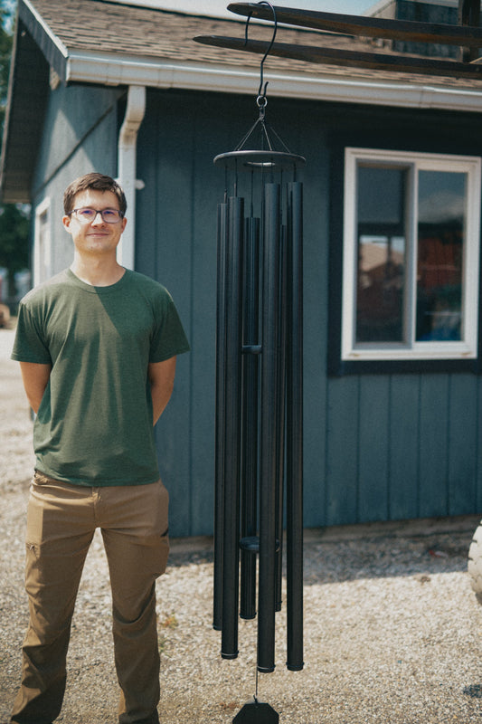 Person standing next to a full-size Twilight Series deep tone wind chime outside the Lambright Country Chimes workshop in Shipshewana, Indiana