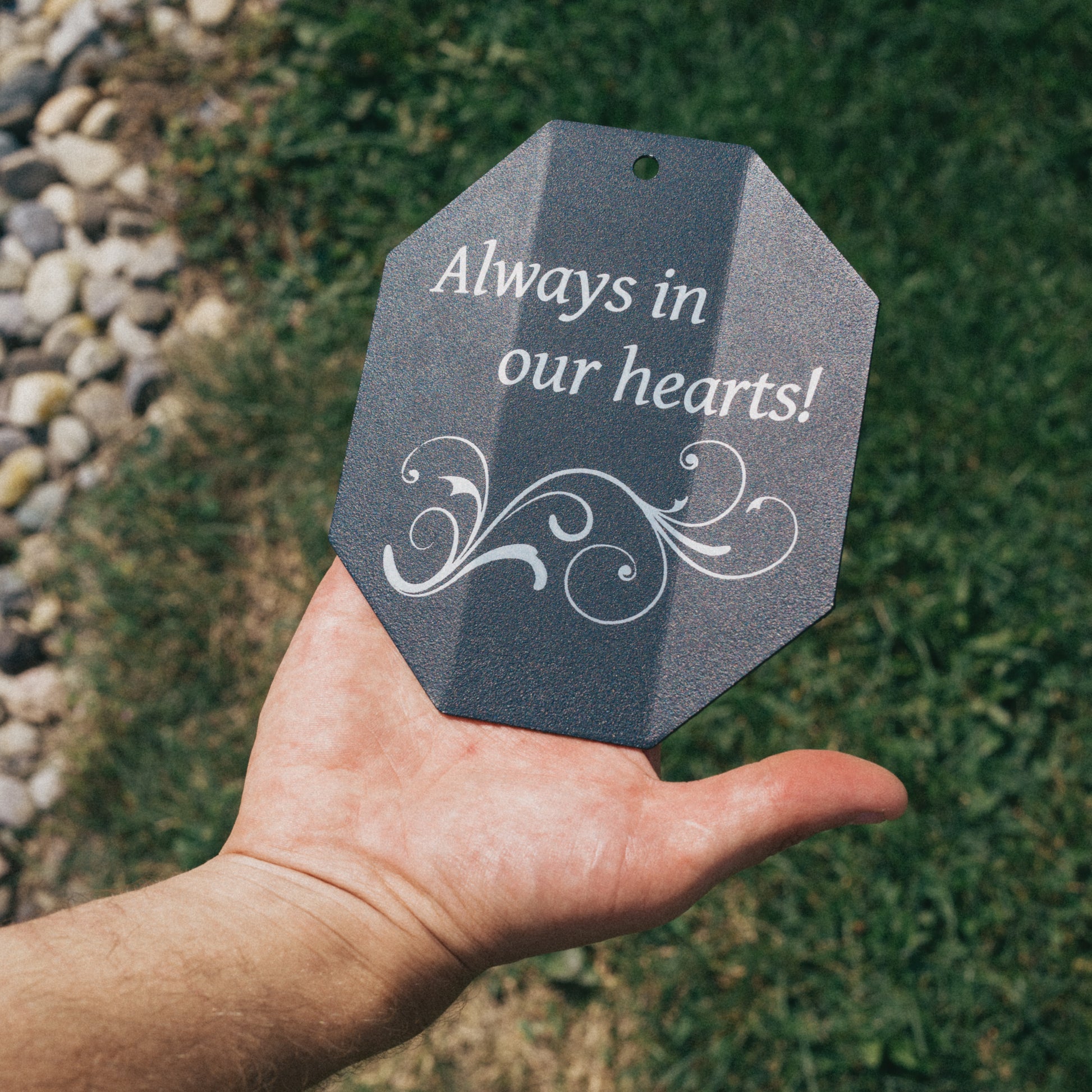 Close-up of a custom engraved wind chime sail with the message 'Always in our hearts!' and decorative scrollwork, perfect for a sympathy or bereavement gift.